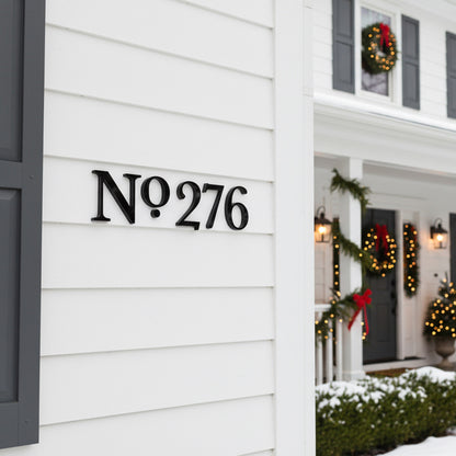 House number 'No 276' on a white wall with Christmas decorations on a porch.