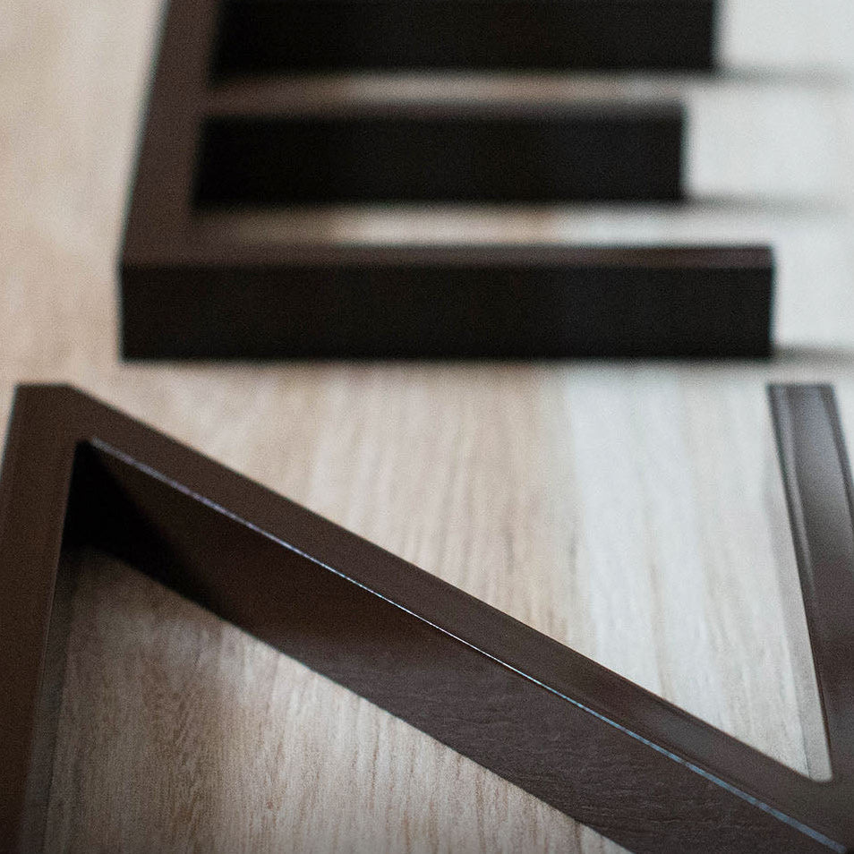 Brown acrylic house number samples on light wood surface showing various sizes and styles. Shown in: Brown · 3/4" Aluminum