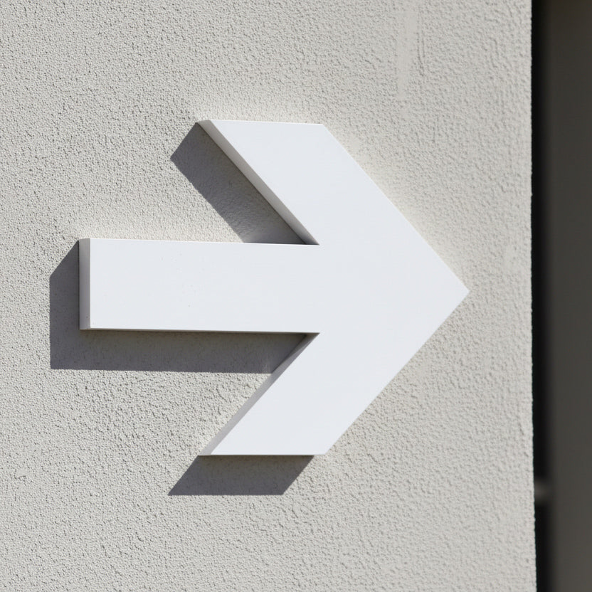 White arrow-shaped object on a textured beige wall