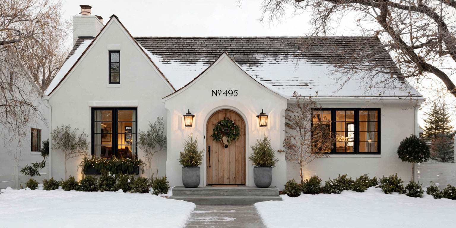 White house with black house numbers in a snowy landscape
