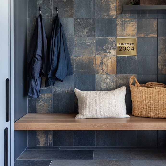 Custom accent tile in solid brass 4 inch square. In a full blue tile mudroom with floating oak bench