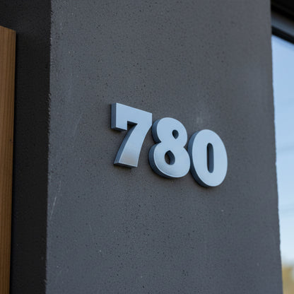 blue House numbers '780' on a textured gray wall.