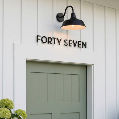 House number 'FORTY SEVEN' displayed on a white wall above a green door.