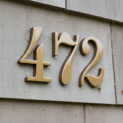 Gold house numbers '472' on a concrete wall