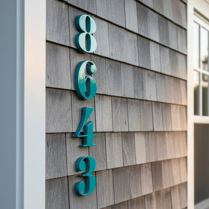 Teal house numbers on a wooden shingle wall