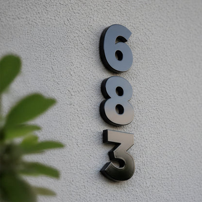 House numbers '683' on a light gray wall with a plant in the foreground.