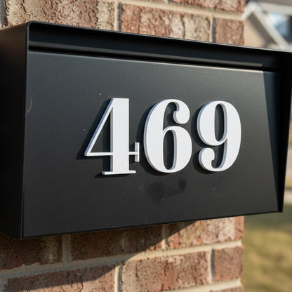 Black mailbox with white house numbers '469' mounted on a brick wall.
