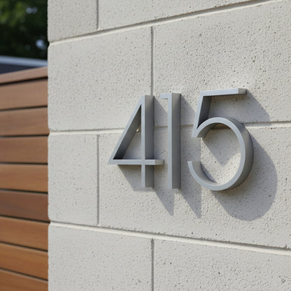 aluminum House numbers '415' on a cinder block wall with wooden paneling.