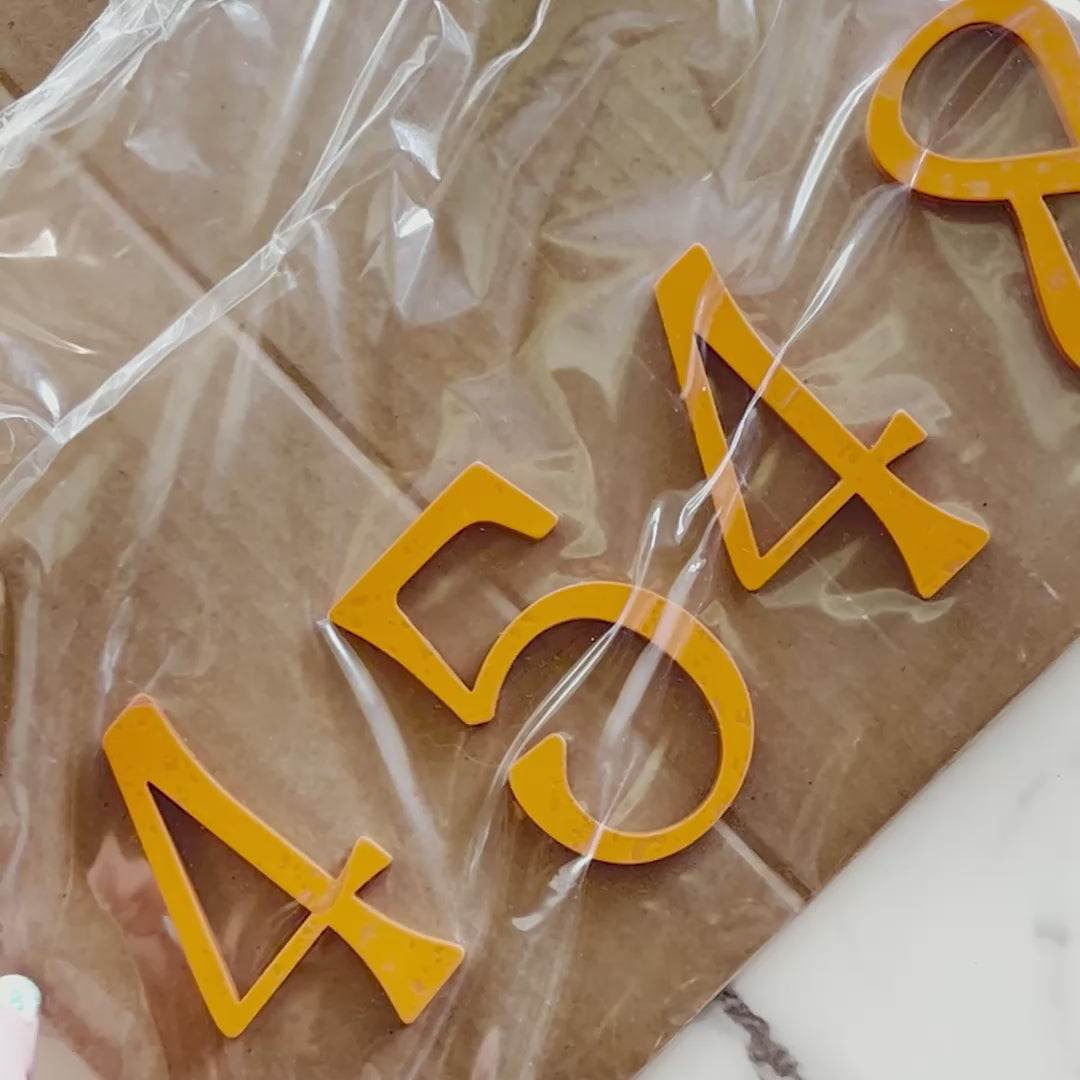 Yellow modern house numbers 4 3 5 4 in packaging on cardboard surface. Shown in: Mangoma · 1/4" Acrylic