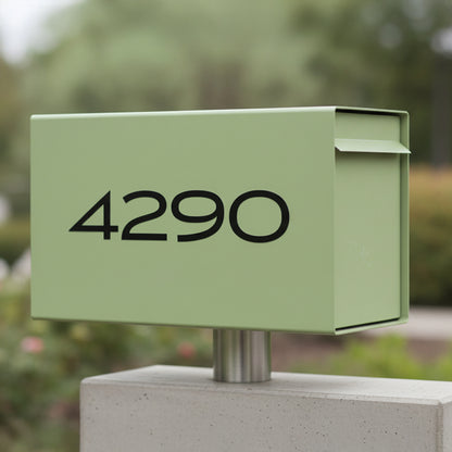 A light sage green metal mailbox mounted on a concrete post outdoors, with the house number 4290 printed in black on the front.