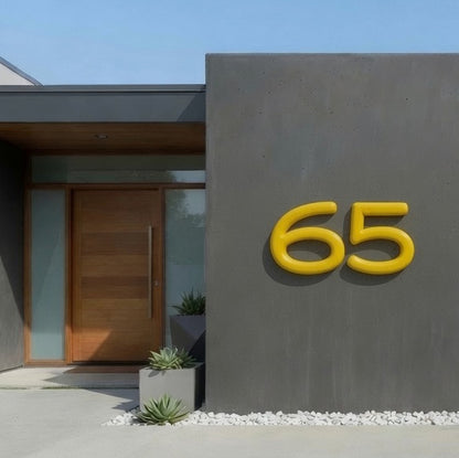 Modern house exterior with a gray wall and yellow house number '65'.
