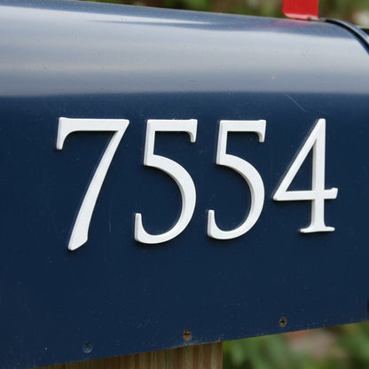 Blue mailbox with white numbers '7554' on a blurred background