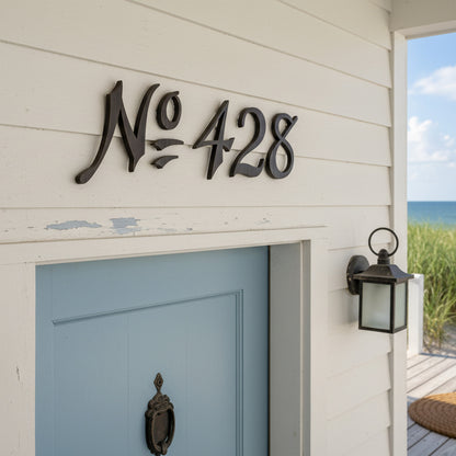 House number 'No 428' on a white wall above a blue door with a lantern on a porch beach house.