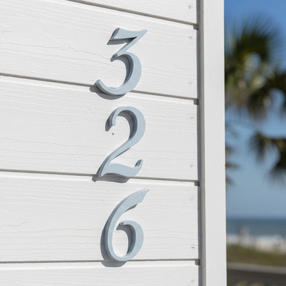 House numbers '326' on a white wall with a blurred outdoor background