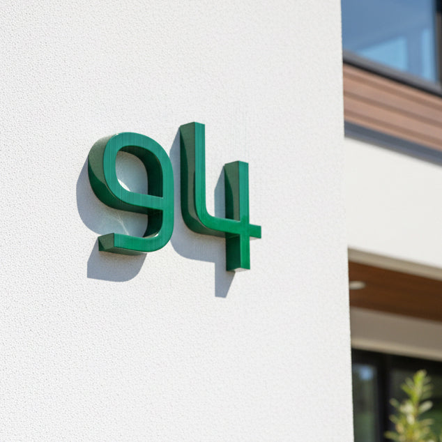 Green house number '94' on a white wall