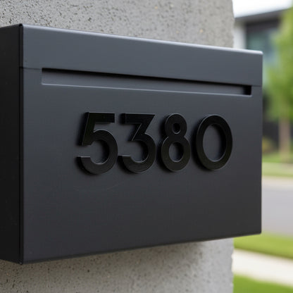 Black mailbox with house numbers '5380' on a concrete wall.