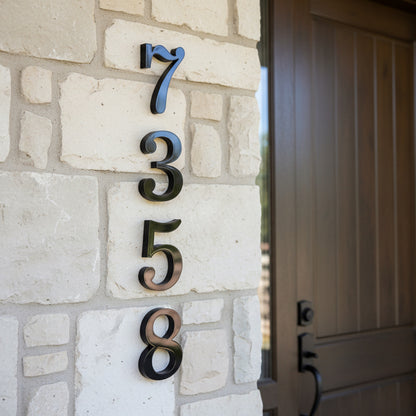 black House numbers '7358' on a stone wall next to a door