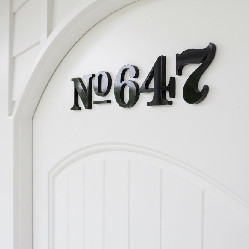 Black house numbers '647' on a white door