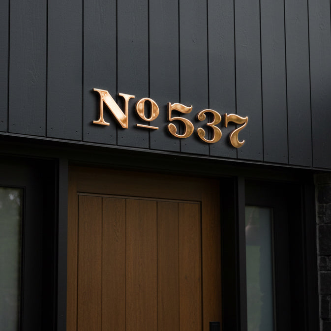 Copper house number 'No 537' on a dark wooden door