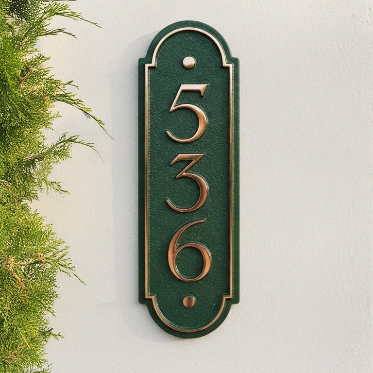 Vertical bronze house number plaque displaying 536 on green background with raised border detail on white wall. Shown in: Bronze · Cast Aluminum