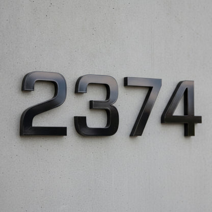 Black metal house numbers '2374' mounted on a light gray textured concrete wall.