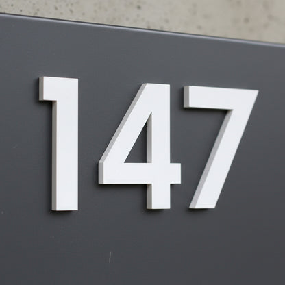White house numbers '147' on a dark gray background