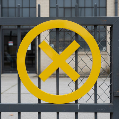 Yellow no entry sign on a black metal gate.